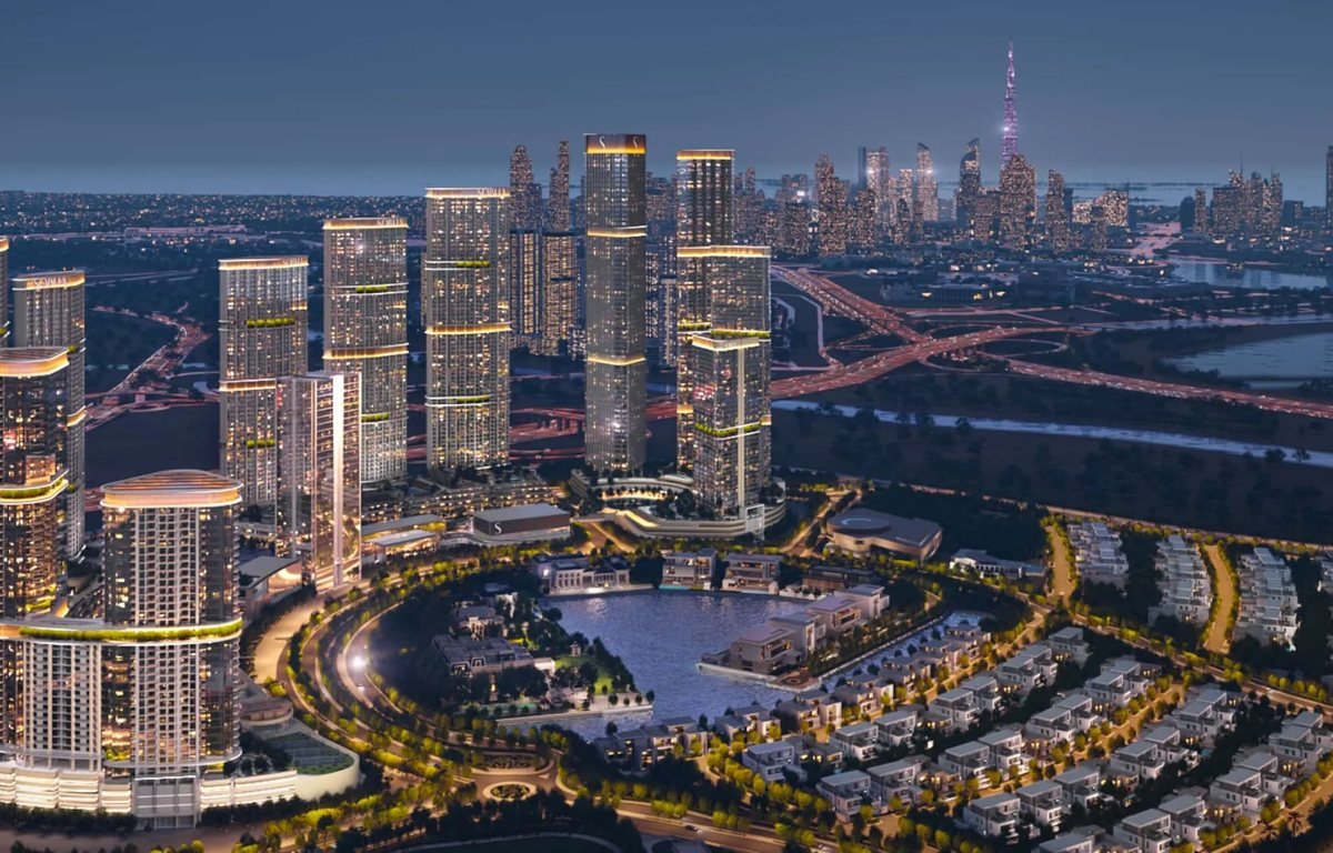 Sobha Hartland II towers and villas at dusk with the Dubai skyline behind
